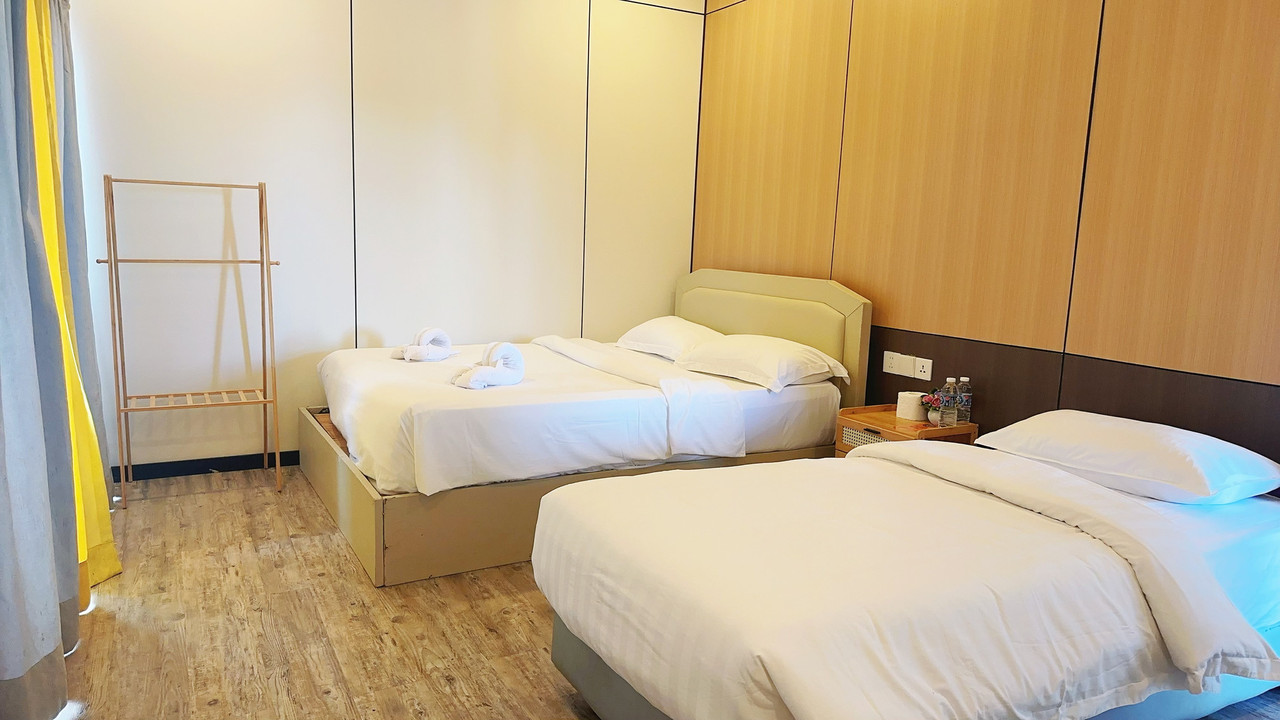 An inviting family room at Sunny Holiday water resort offering two large beds, modern style wooden clothing rack, light wood paneled walls, polished wood floors, and AC.