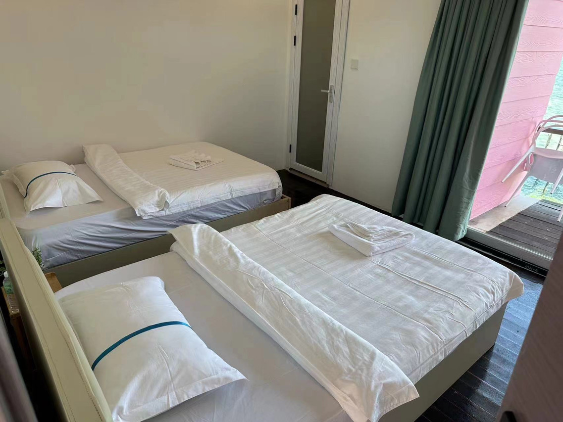 A relaxing bedroom at Sunny Holiday near Pulau Bum Bum offering two large beds, modern style curtains, dark timber floors, air con, and sliding glass doors opening onto the balcony.